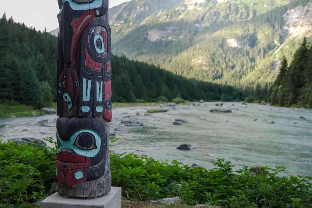 Totem with a river and mountains in the background.